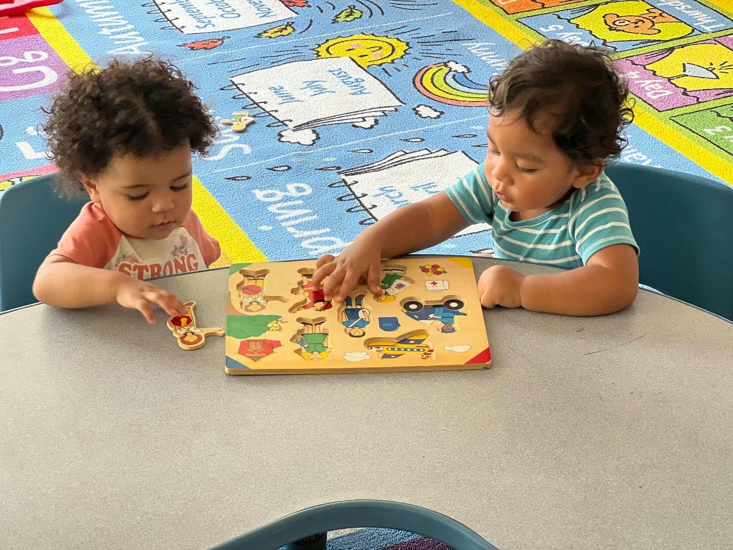 Two children playing with a wooden puzzle at a table