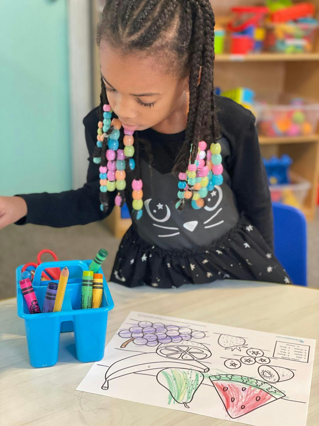 Child coloring a fruit picture in a classroom