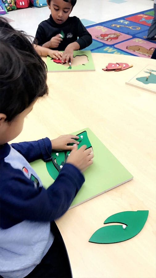 Two children playing with leaf-shaped puzzles at a table