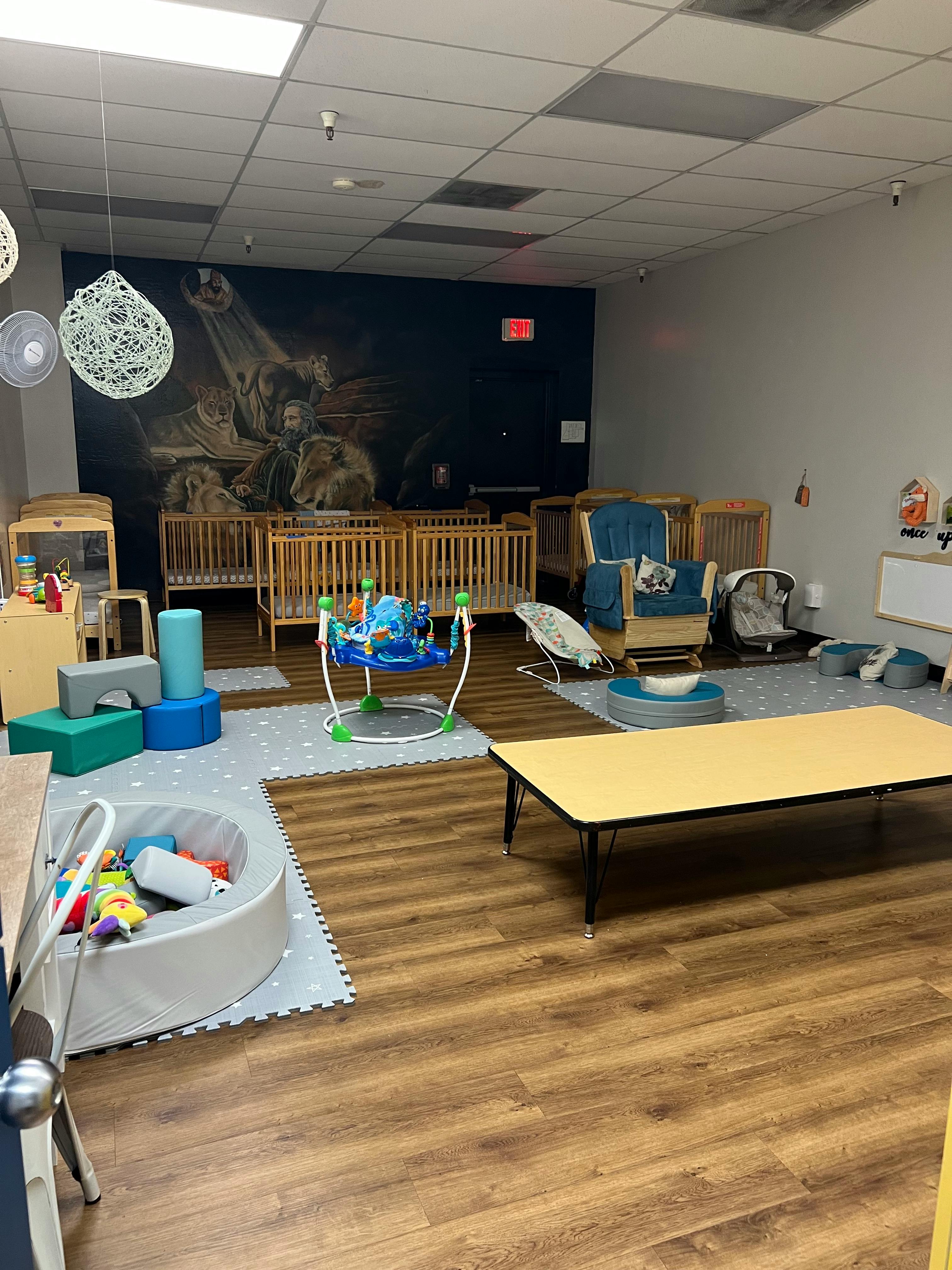 Nursery room with cribs, play mats, and a low table