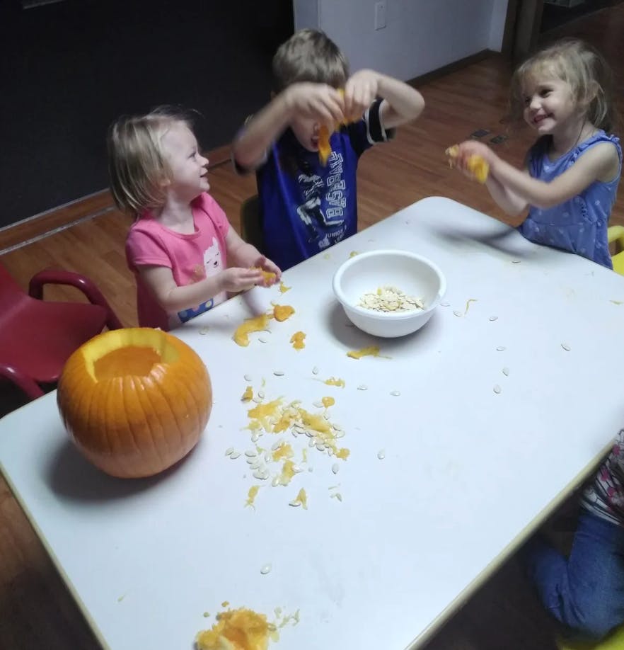 Children cleaning out pumpkins at pumpkin at pumpkin on a table