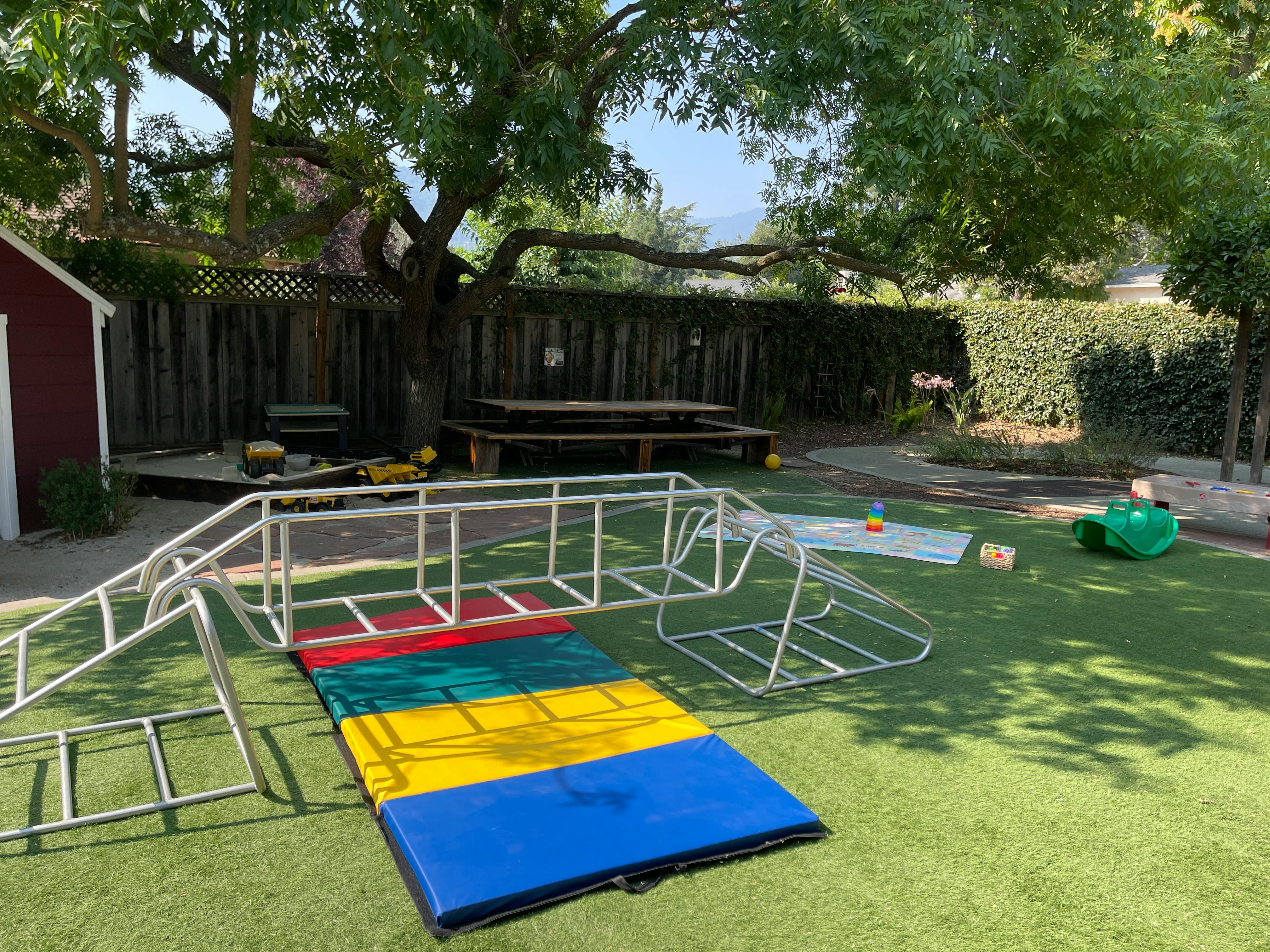 Outdoor play area with climbing equipment and colorful mats