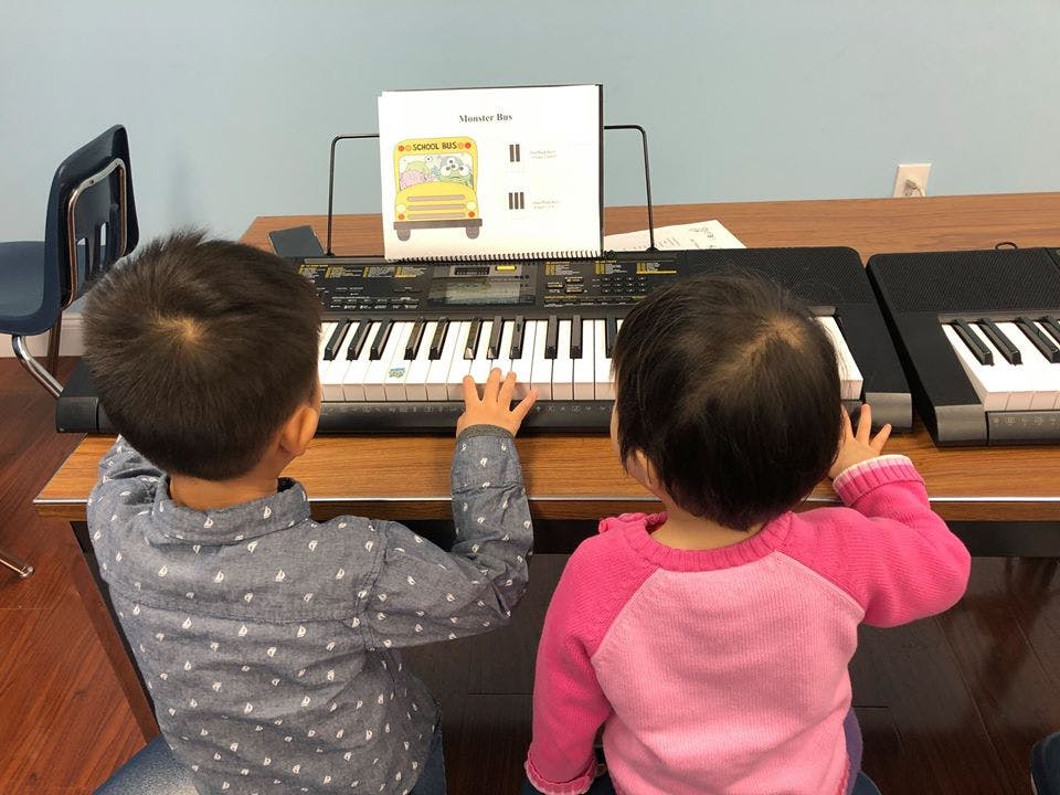 Two children playing on electronic keyboards