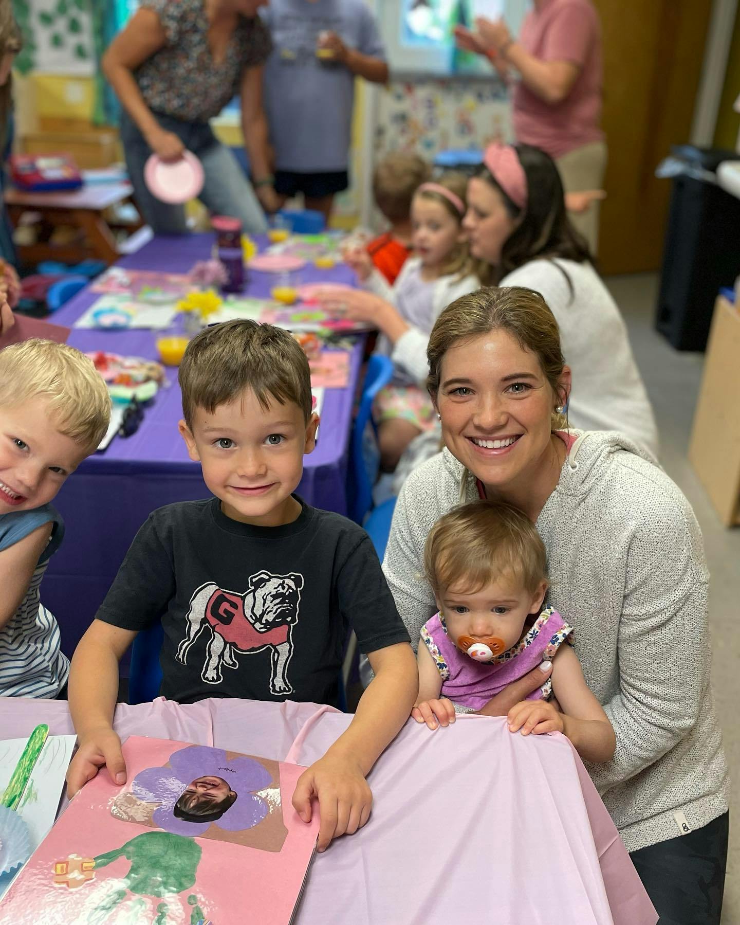 Adult and three children at a table with art supplies
