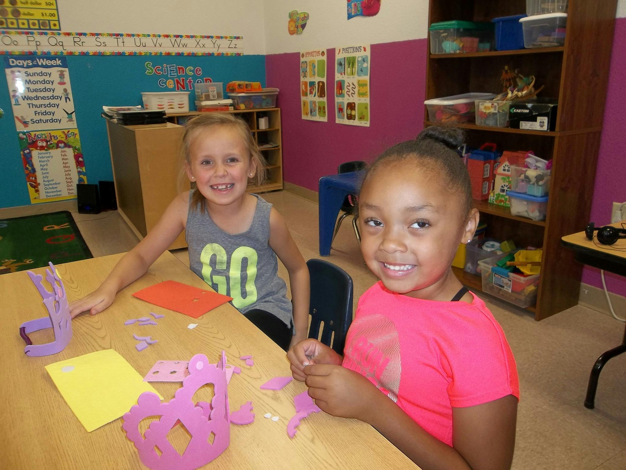 Two children sitting at a table with craft supplies