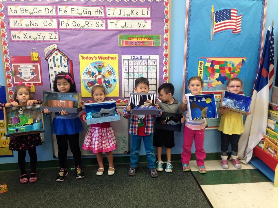 Six children holding up their artwork in a classroom