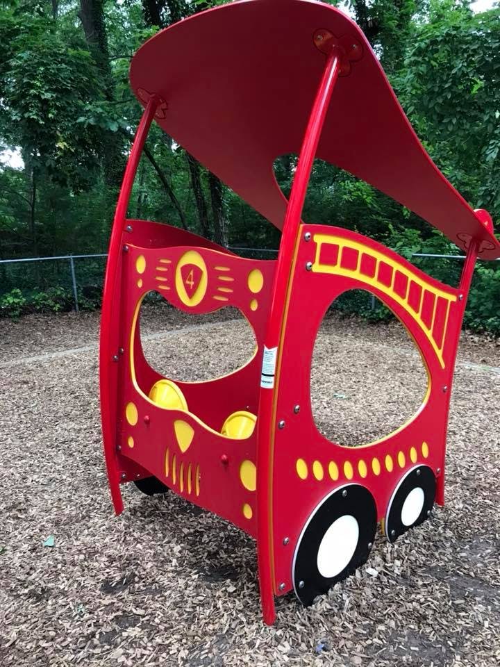 Red fire truck play structure on wood chips