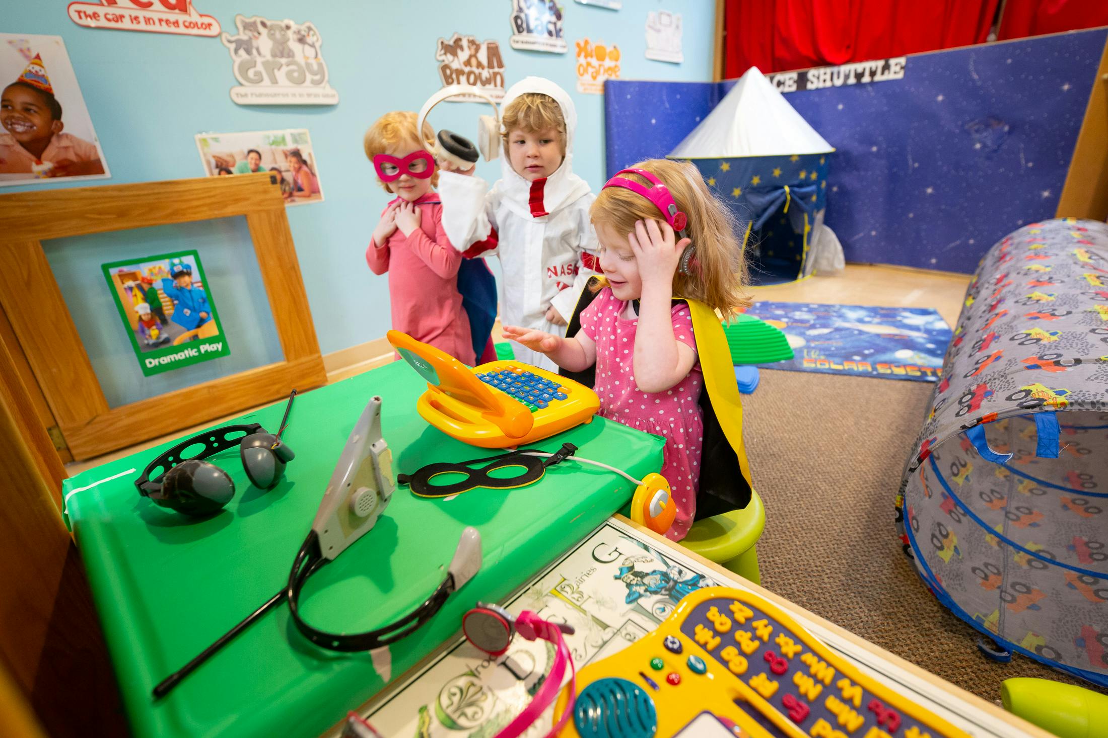Three children playing with toys in a room