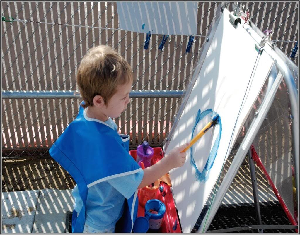Child painting on an easel outdoors
