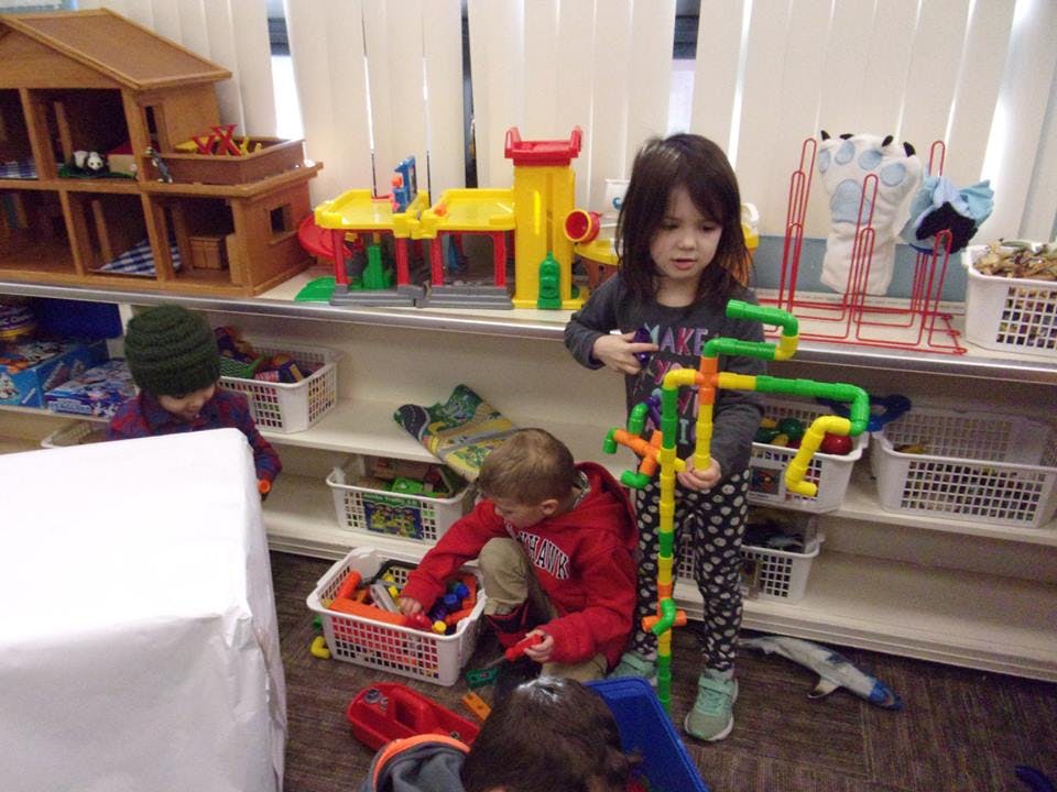 Three children playing with toys in a classroom