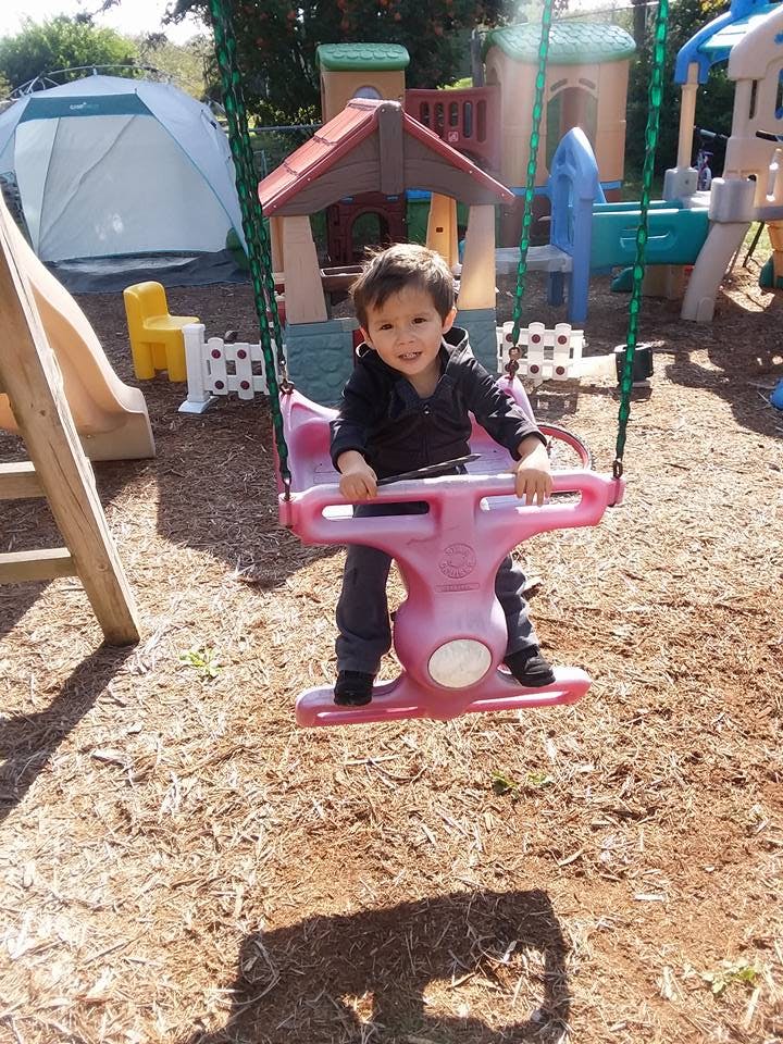 Child in a pink swing on a playground