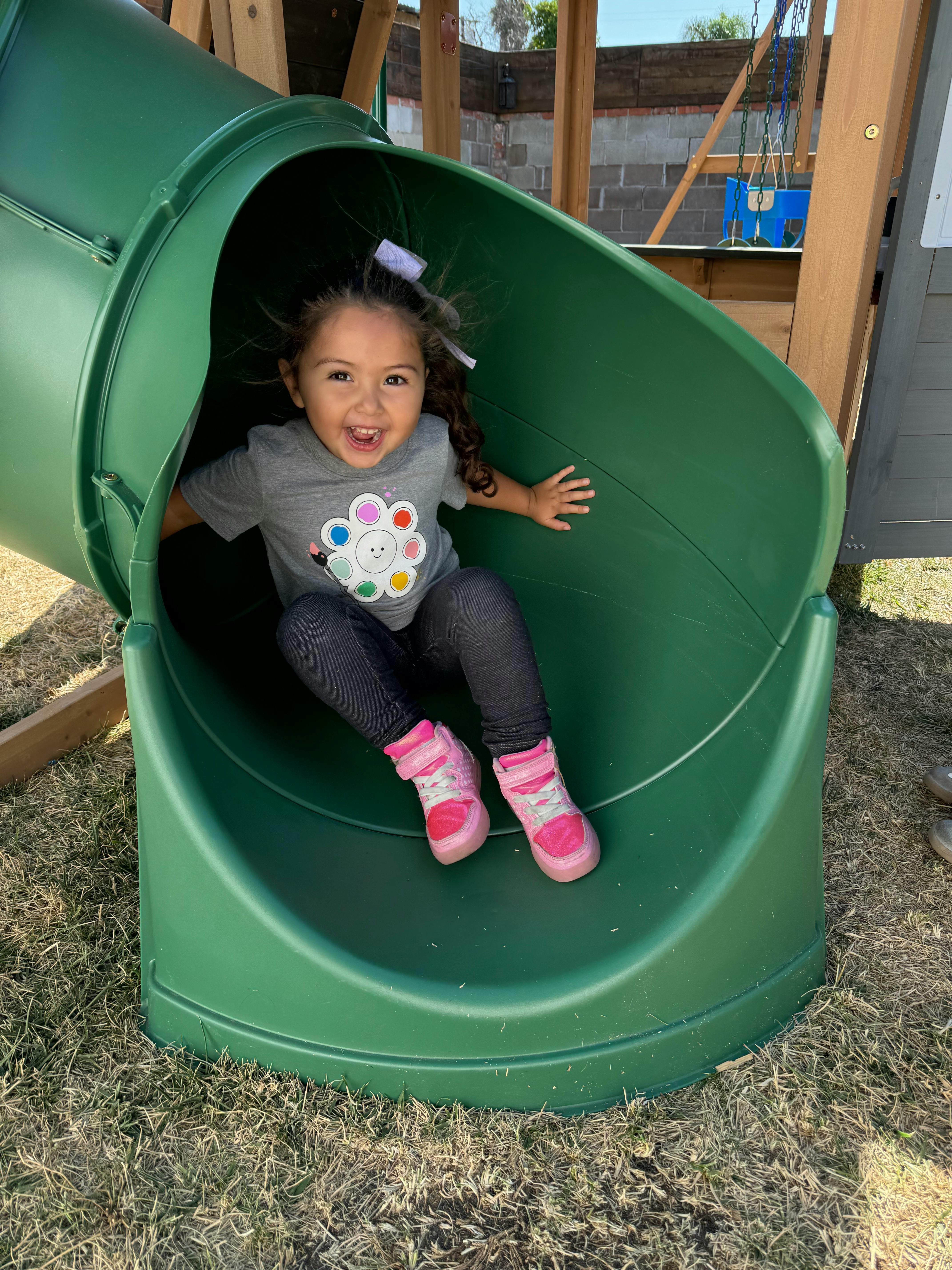 Child sliding down a green playground slide
