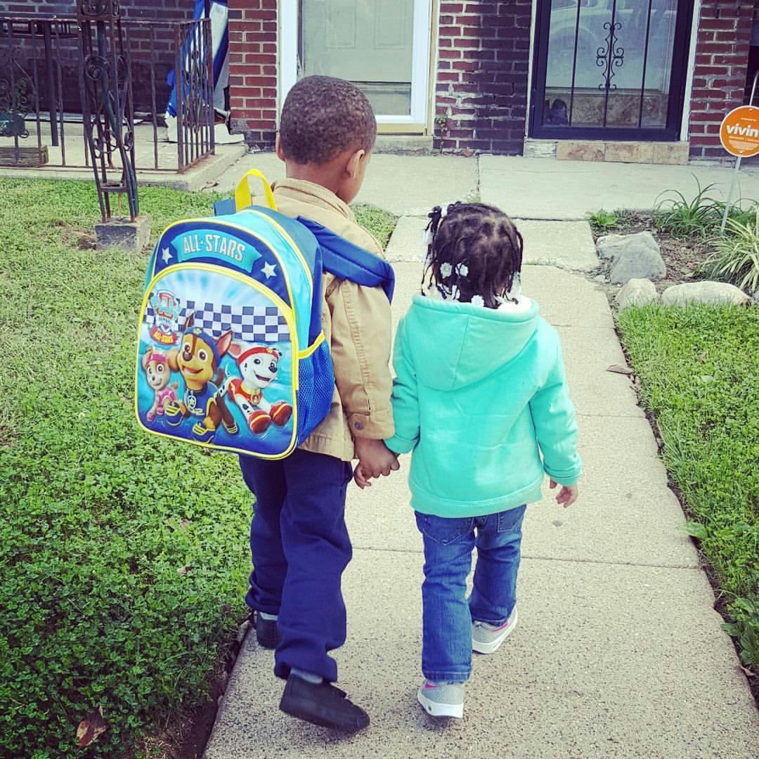 Two children holding hands and walking away from the camera