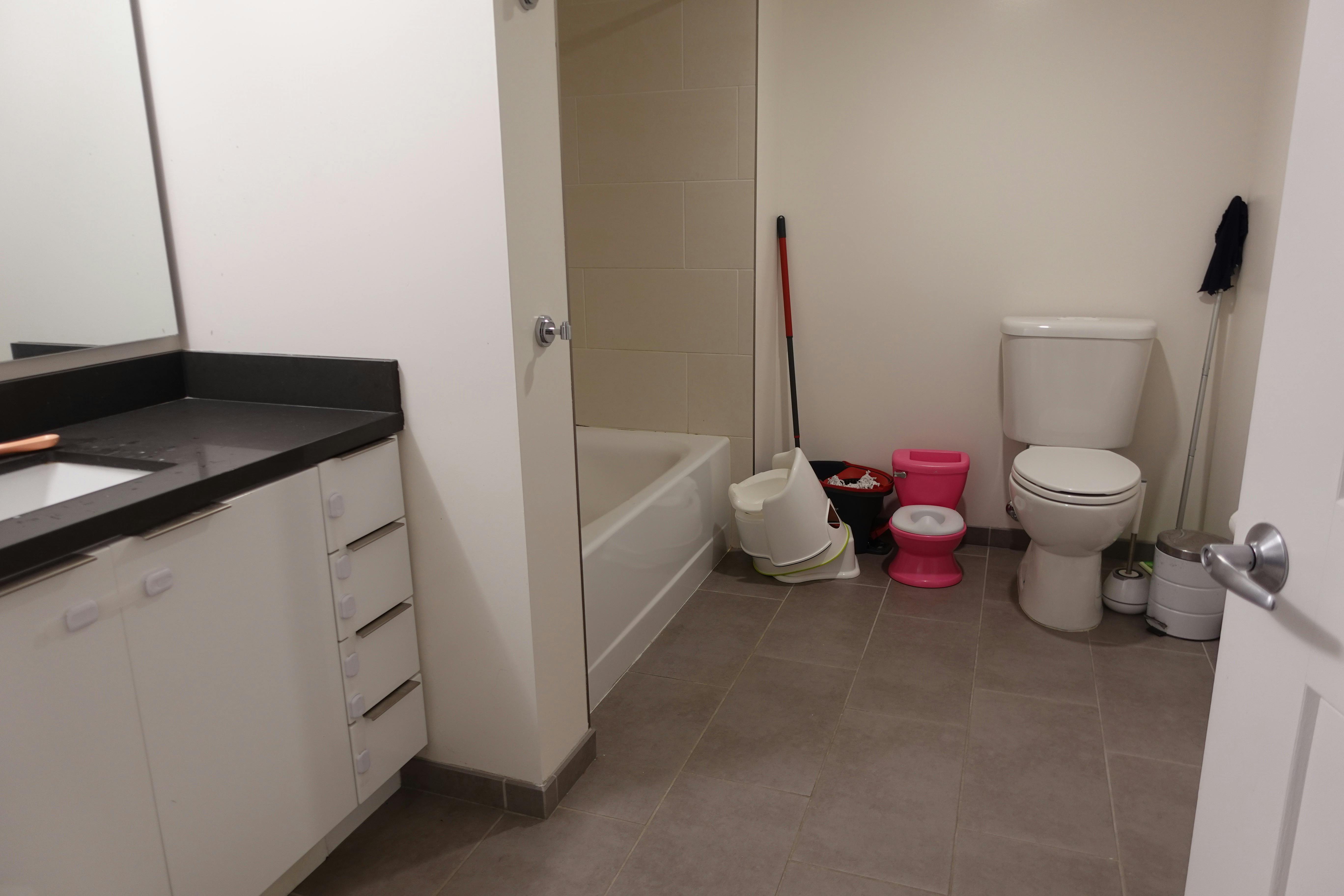 Bathroom with a vanity, bathtub, toilet, and child potty training seats