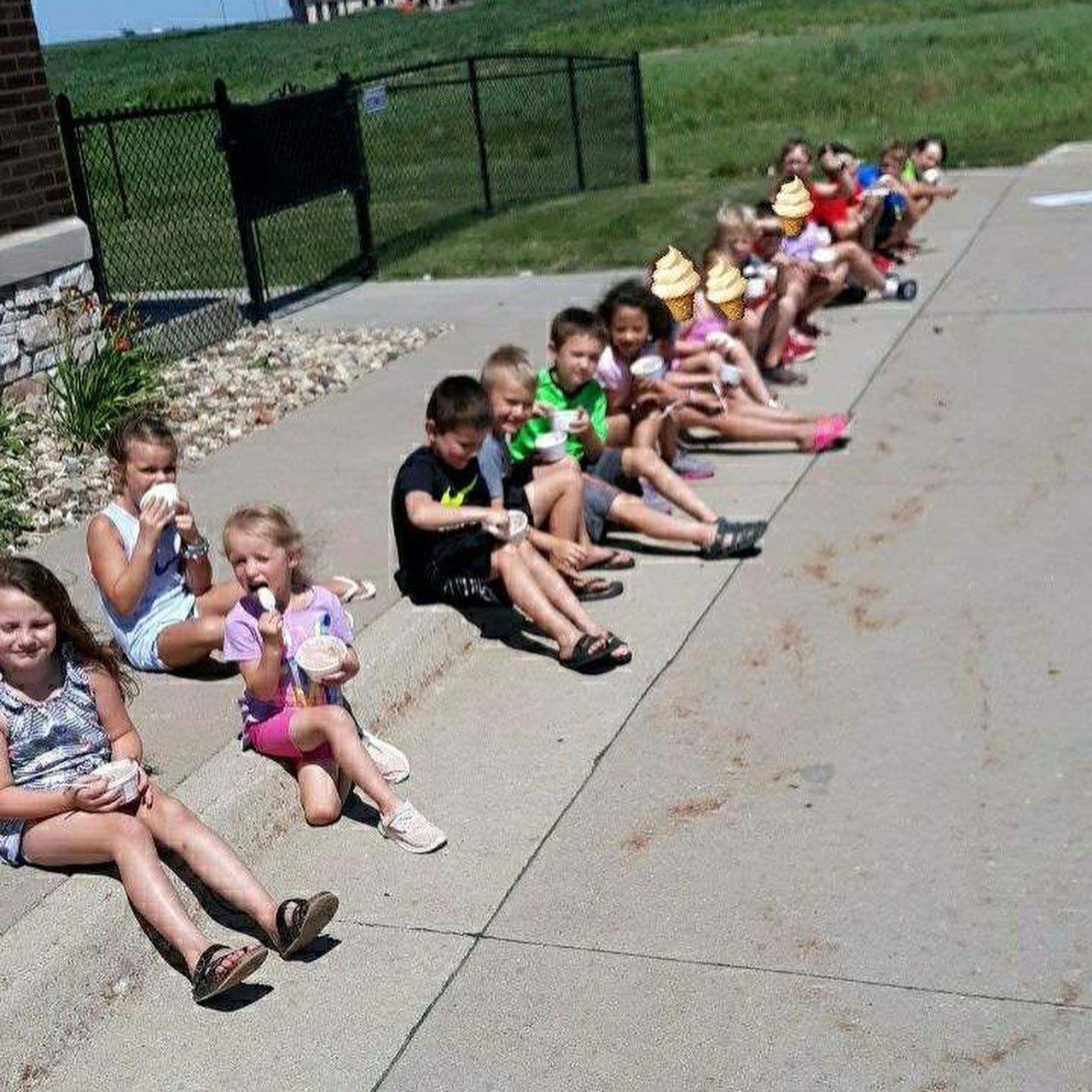 Children sitting on a curb eating ice cream