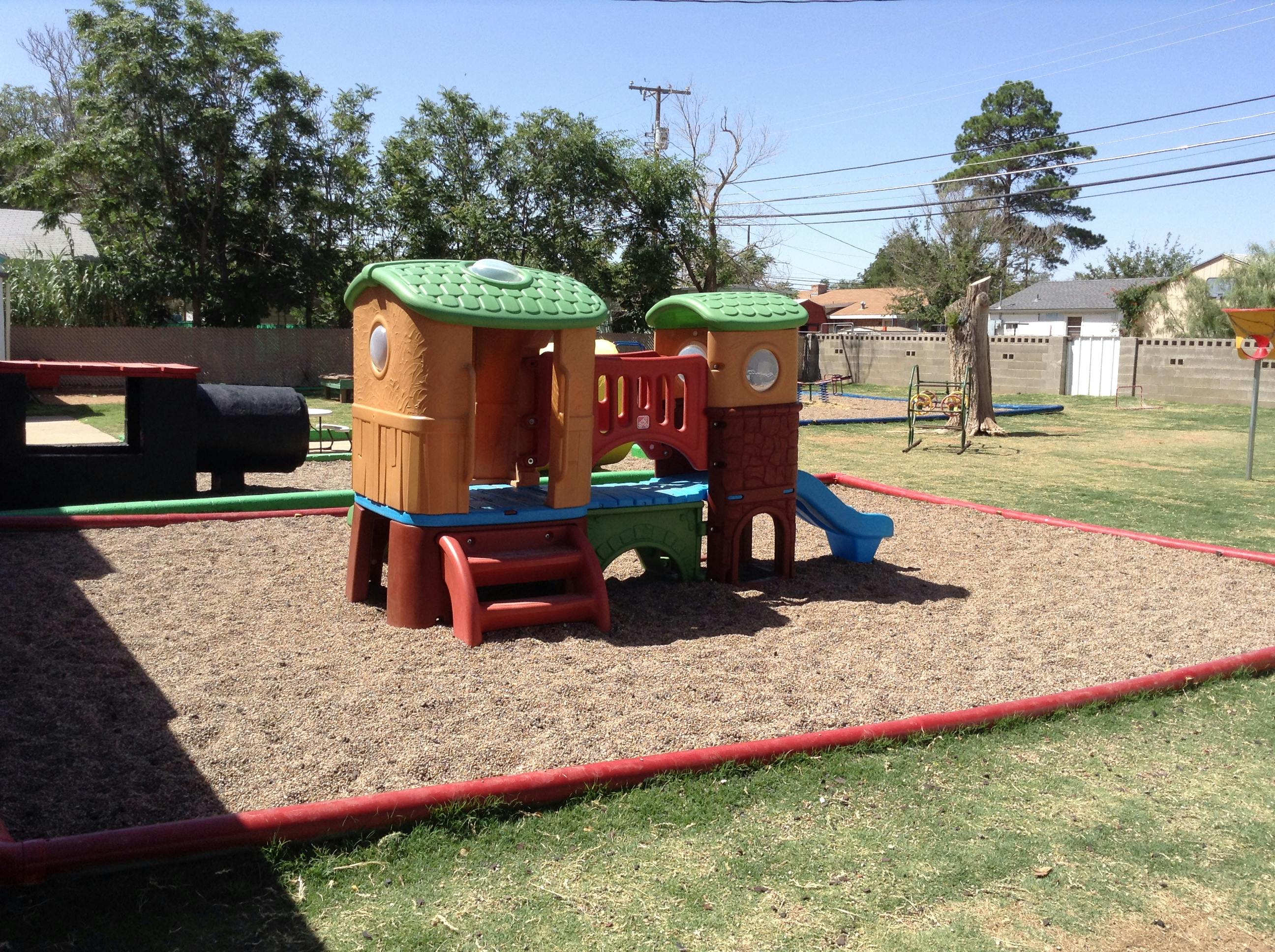 Playground with a play structure and sand area covered sandbox area on the ground with sand
