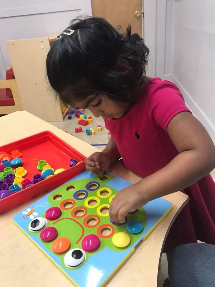 Child playing with a colorful pegboard toy on a table