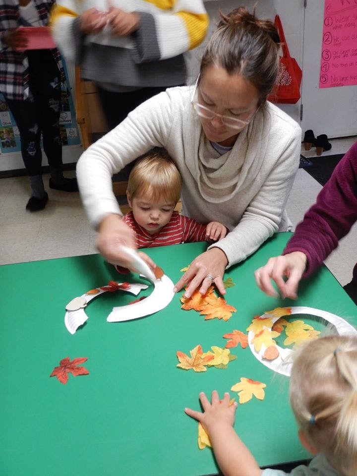 Adult and child making crafts with paper plates and fall leaves
