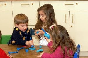 Three children playing with modeling clay at a table