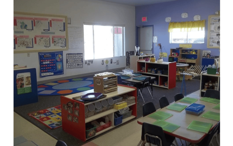 A colorful classroom with child-sized tables and chairs, and learning materials