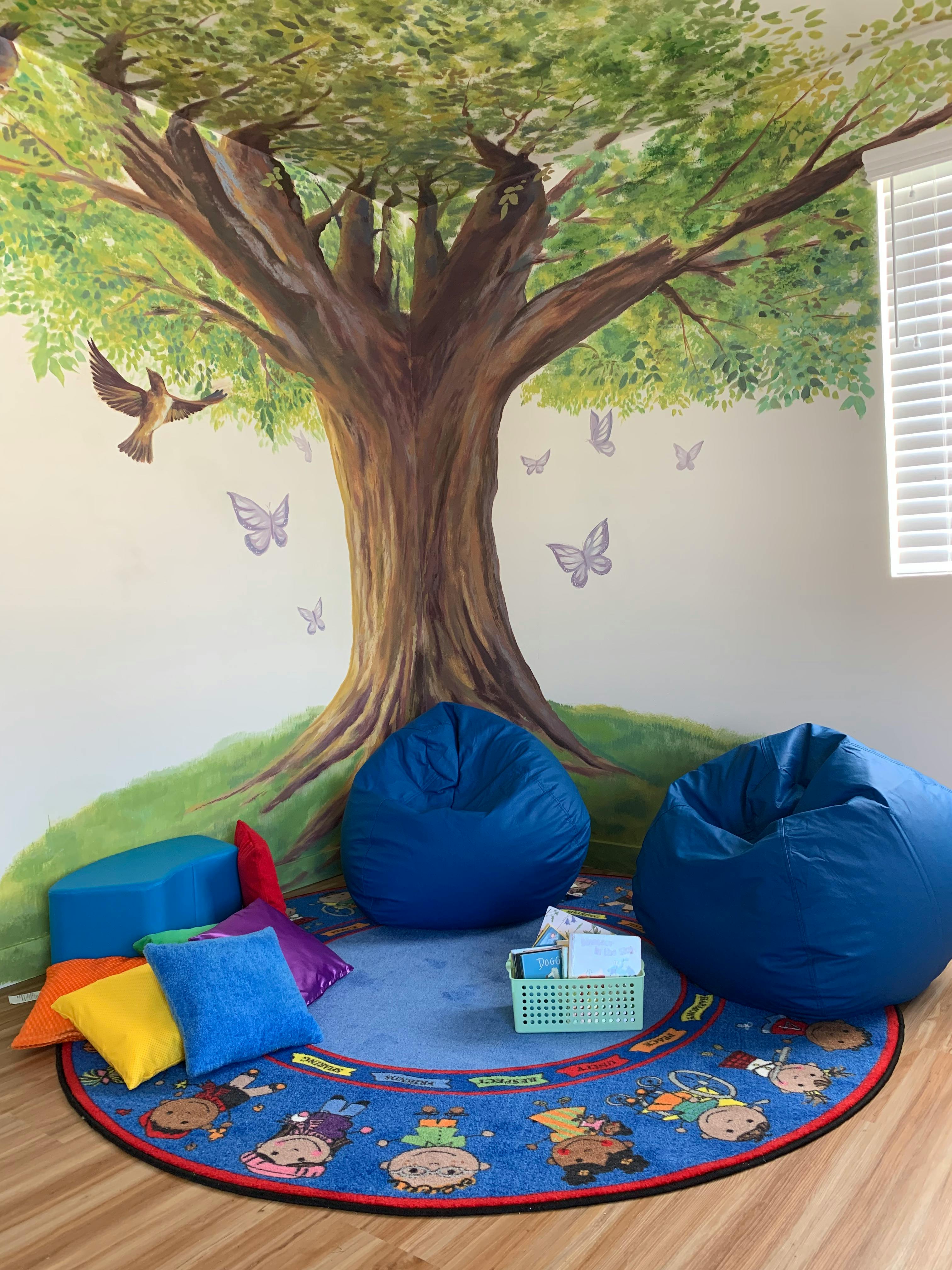 Tree mural with blue beanbags and a round rug