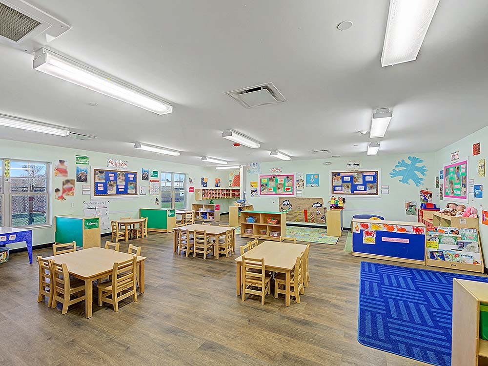 Empty colorful children's classroom with small wooden tables and chairs