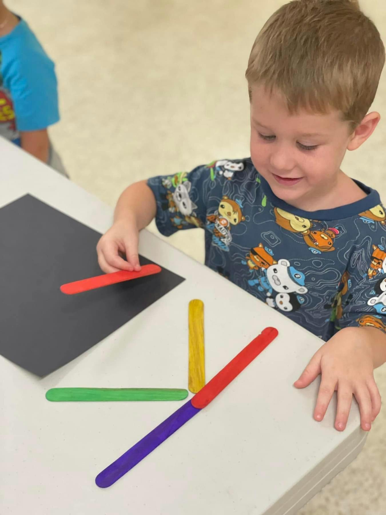 Child playing with colorful craft sticks on a table