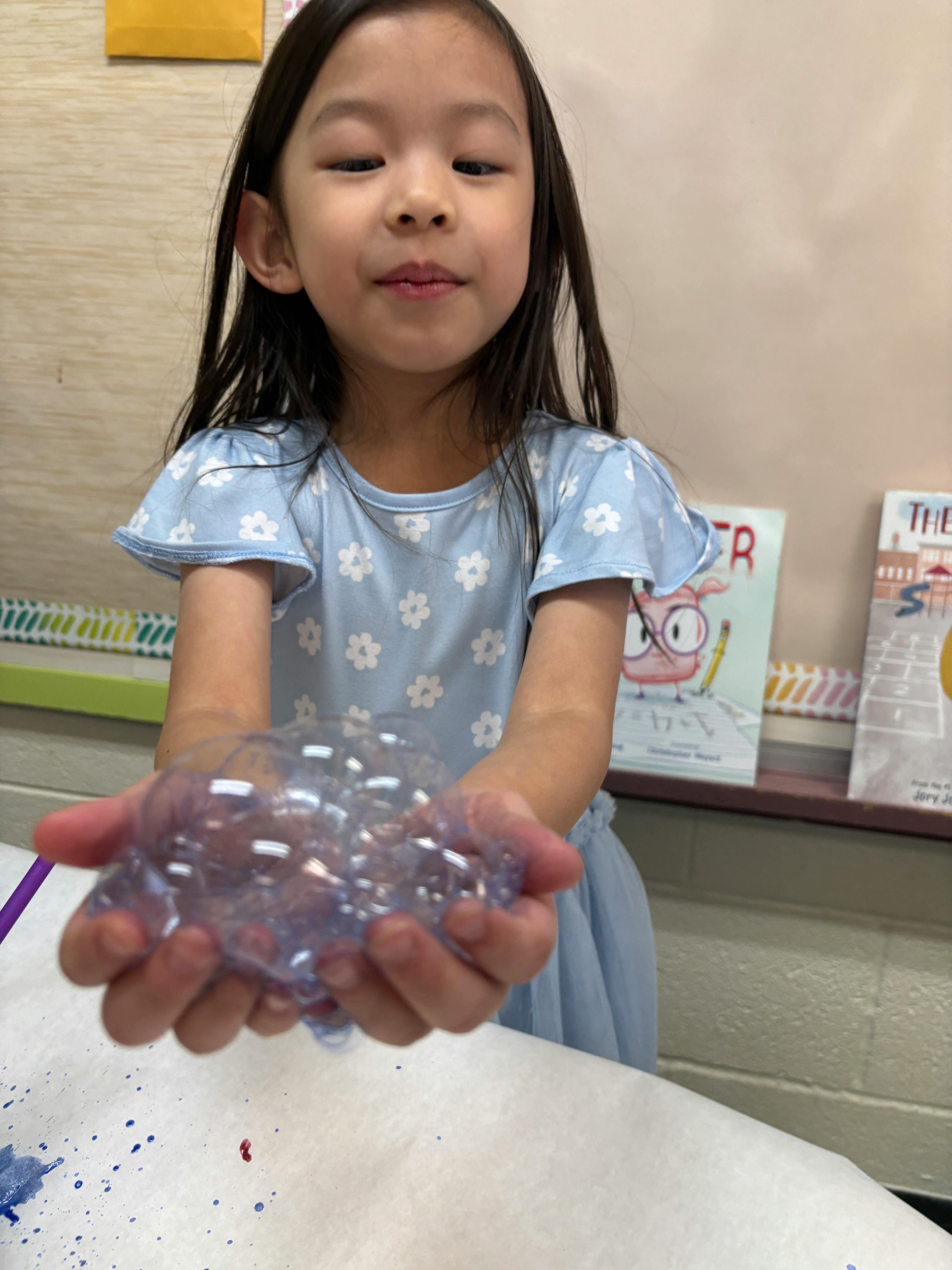 Child holding a cluster of bubbles in cupped hands