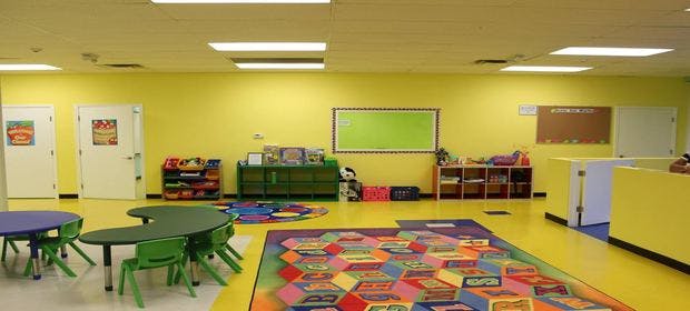 Empty classroom with small tables and chairs, colorful rug