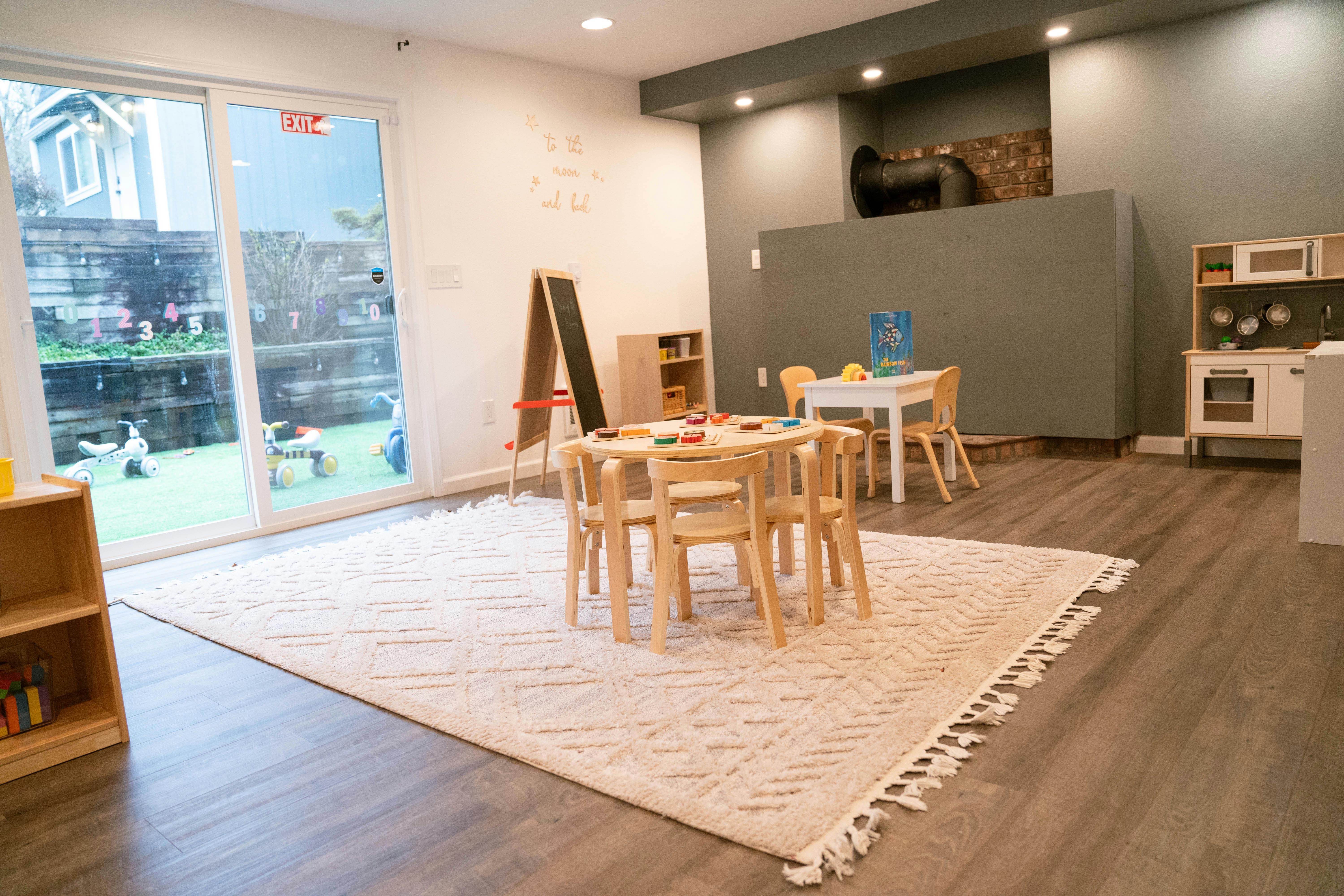 Playroom with small wooden tables and chairs on a rug