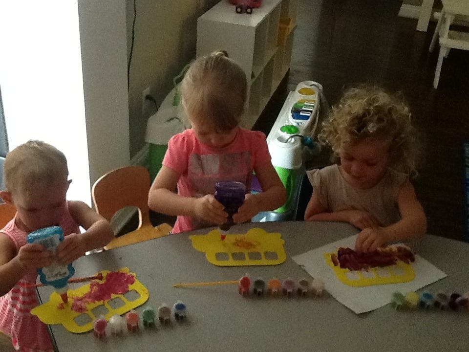 Three children painting at a table