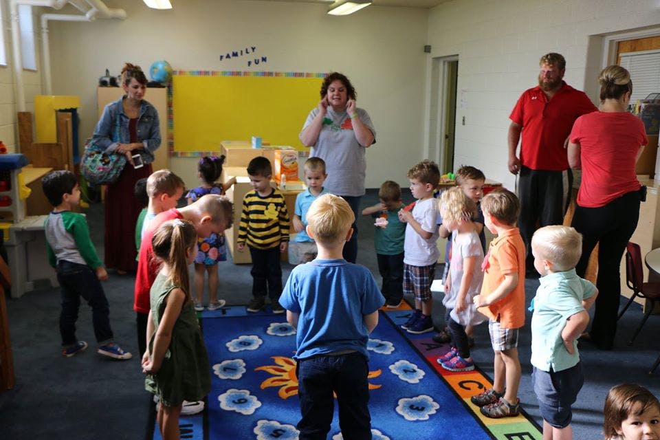 Adults and children standing in a classroom