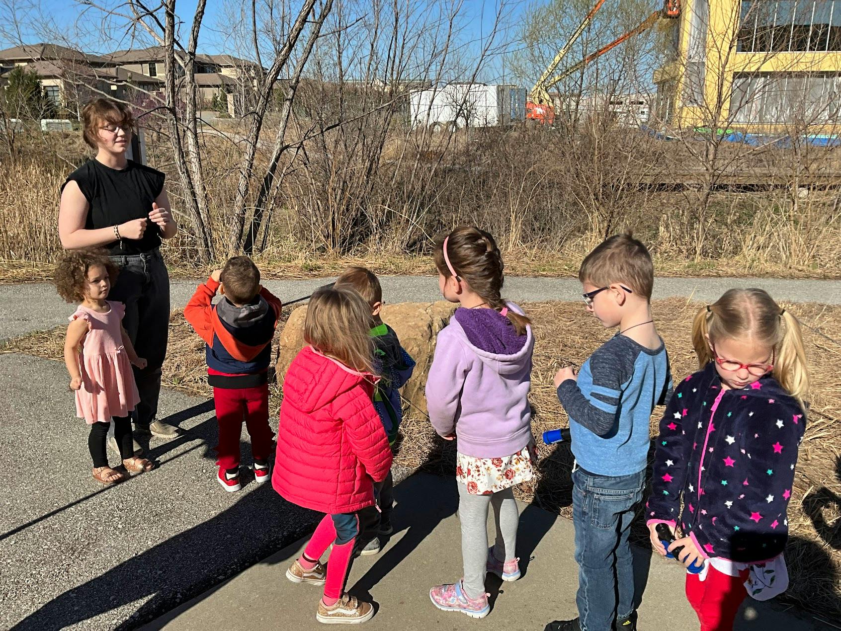 Adult and several children standing outdoors