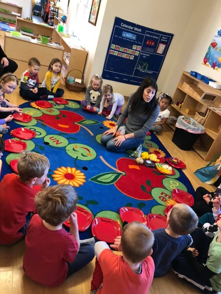 Adult and children sitting on a rug in a classroom
