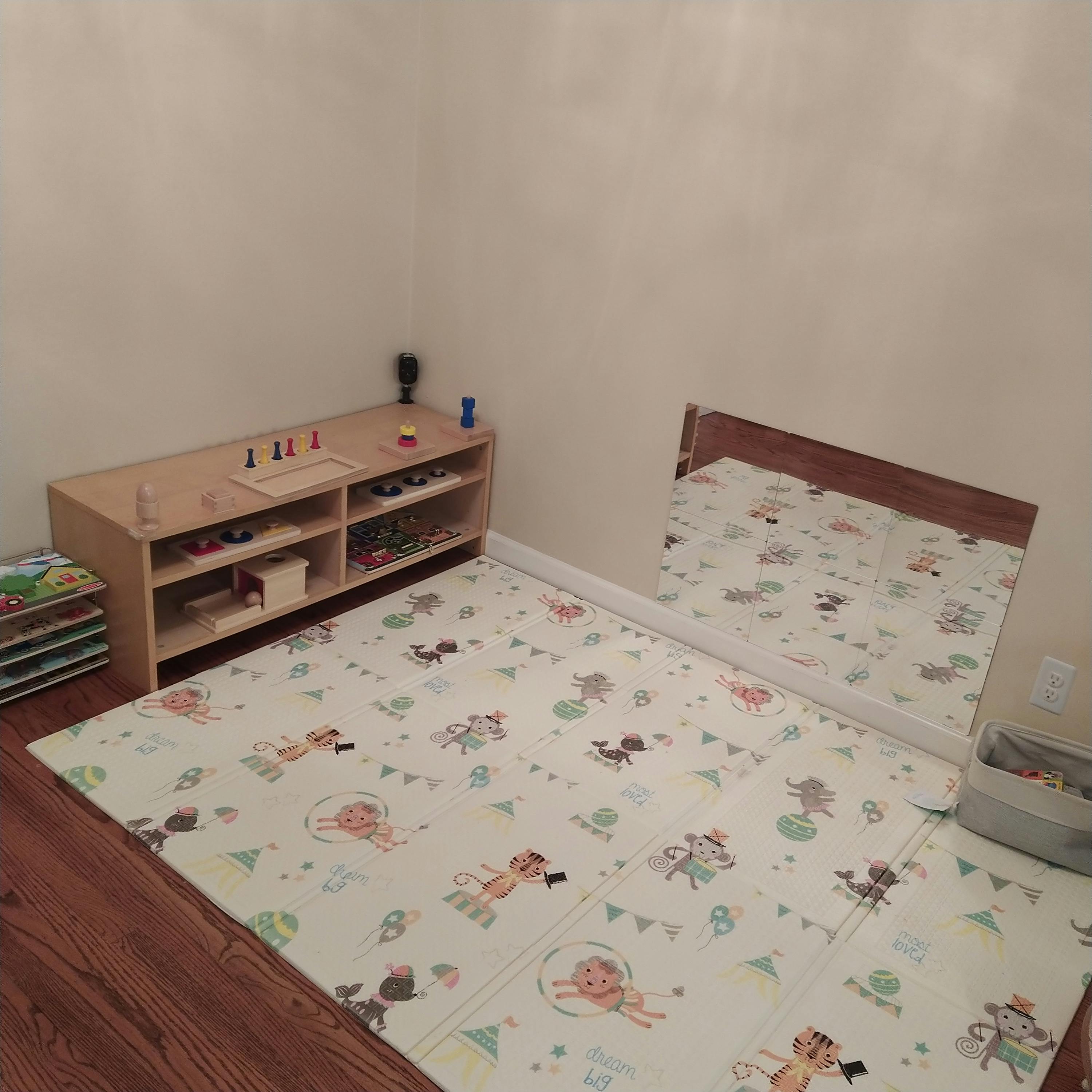 Playroom with a low wooden shelf, playmat, and mirror
