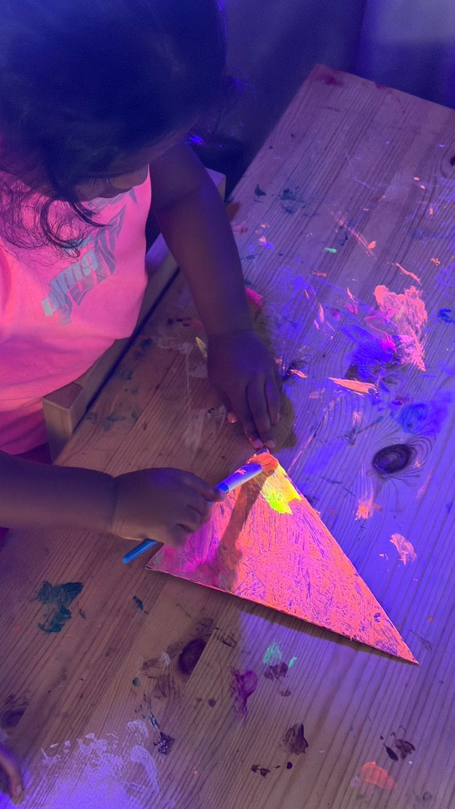 Child painting a triangle shape with glow-in-the-dark paint