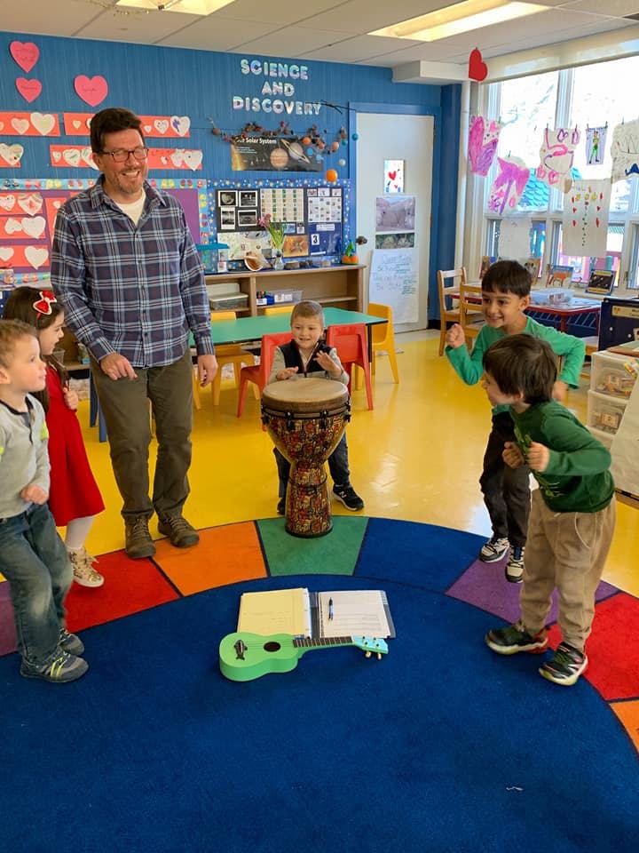 Adult and children in a classroom with musical instruments