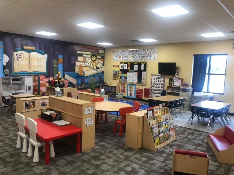 Classroom with small tables and chairs, book displays, and wall murals
