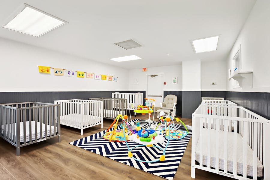 Nursery room with multiple cribs and a play mat with toys