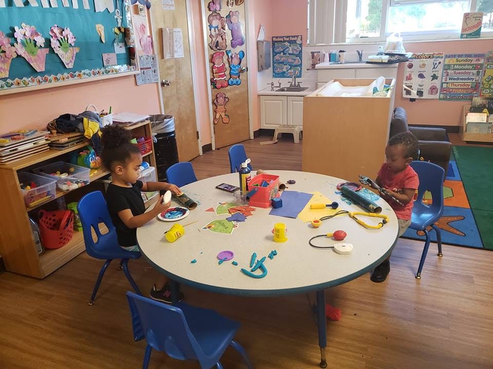 Two children playing at a round table in a classroom