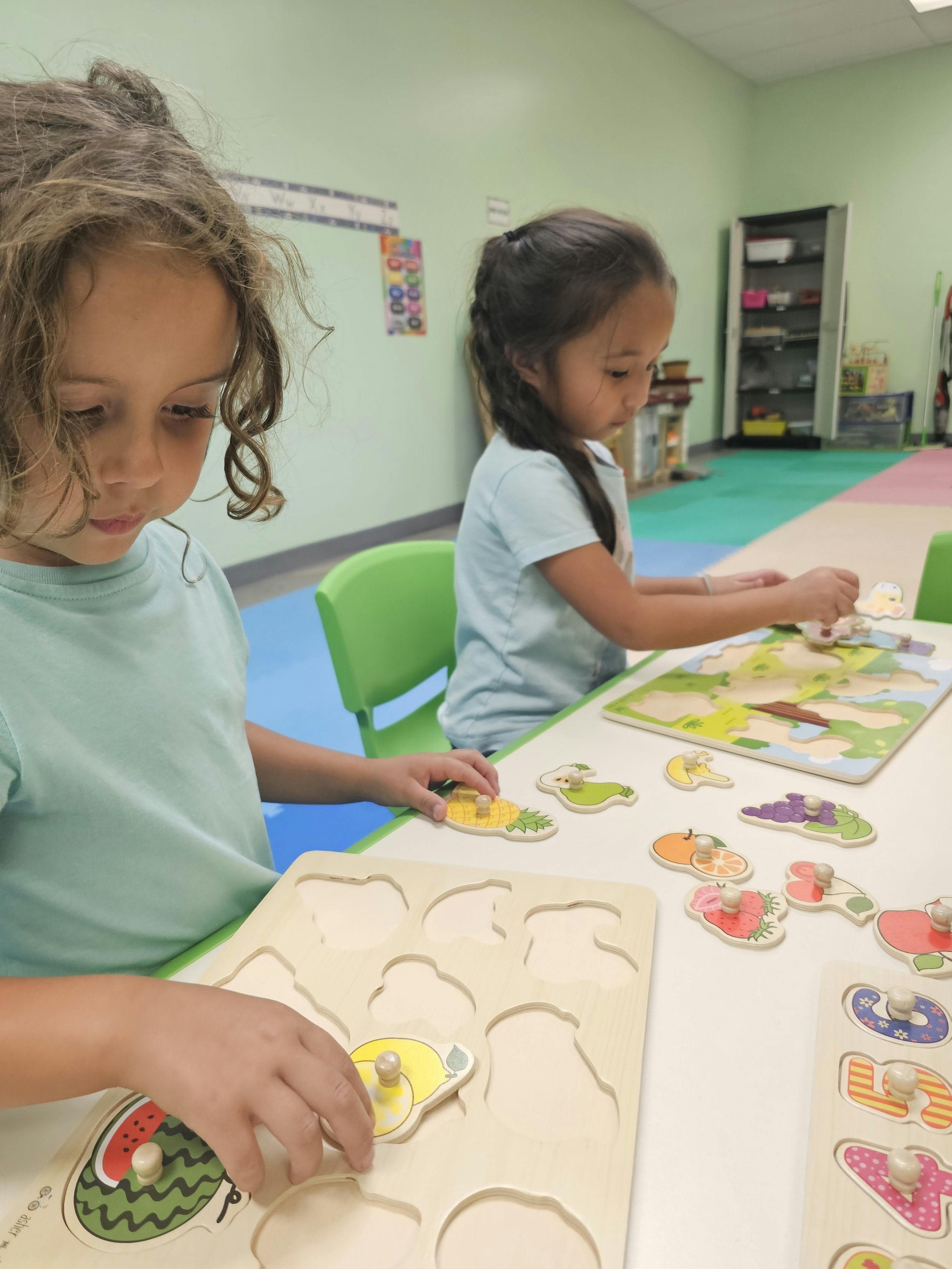 Two children playing with puzzles at a table