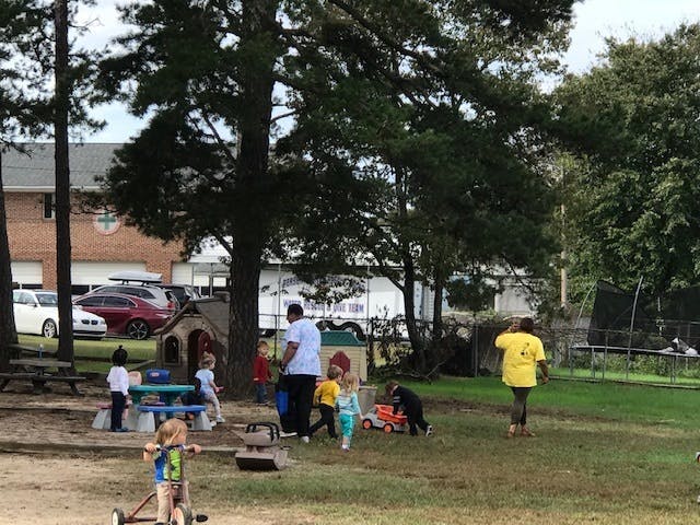 People and children playing outdoors in a grassy area