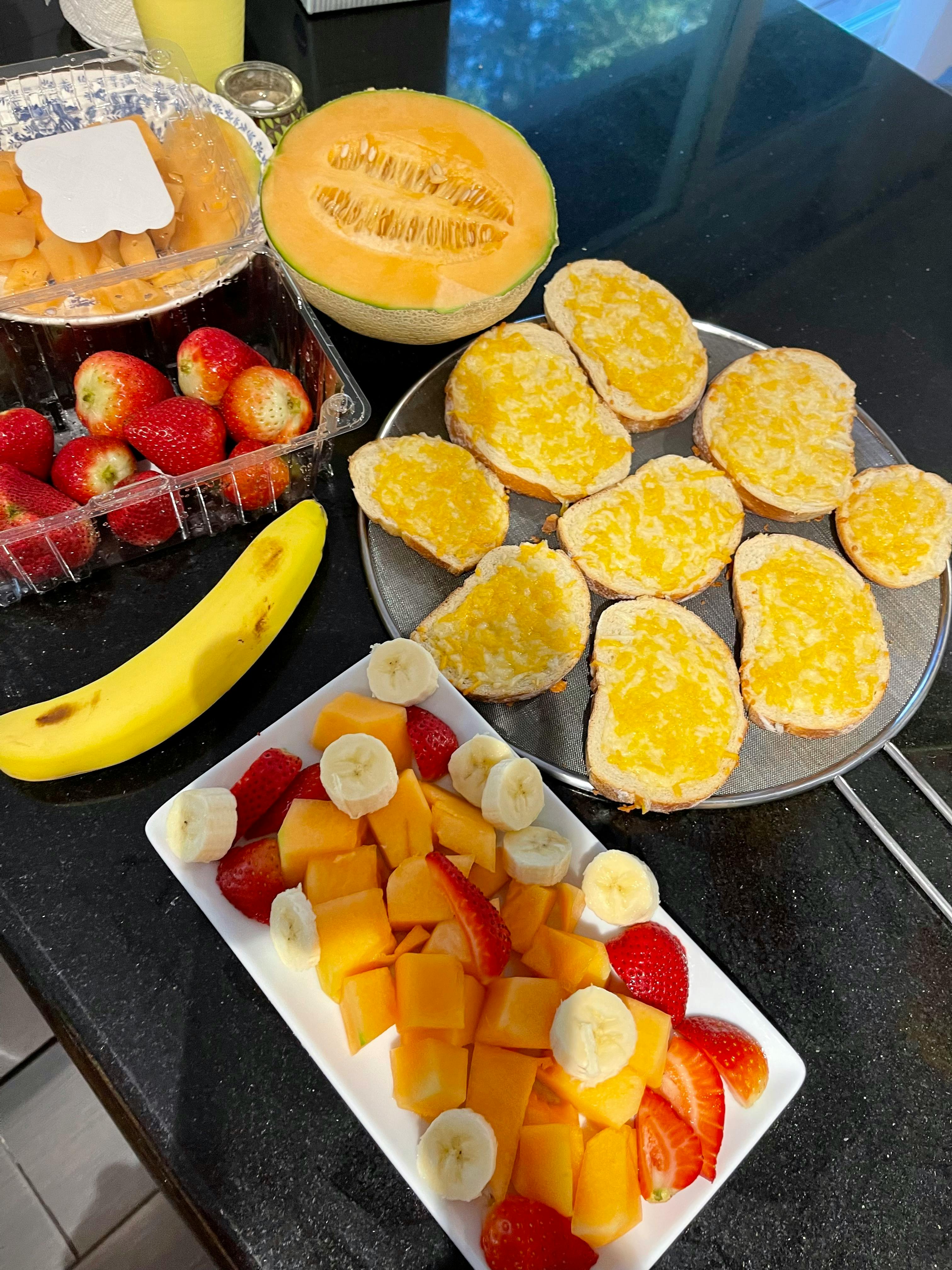 Various fruits and cheesy bread on a counter