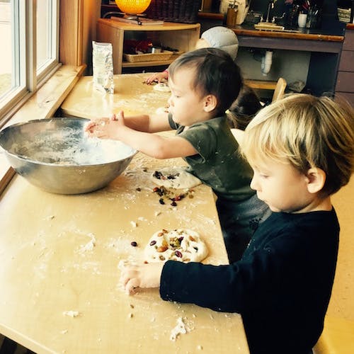Two children making dough on a flour-dusted counter