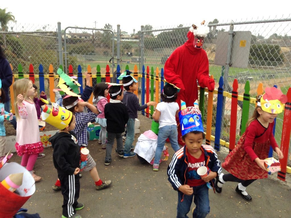 Children in party hats with a person in a red costume