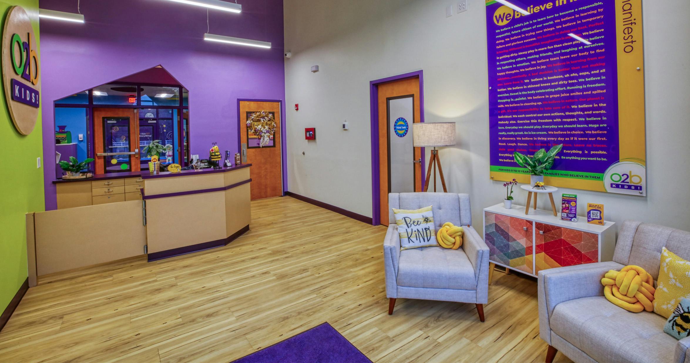 Reception area of a children's center with a counter, seating, and a large sign