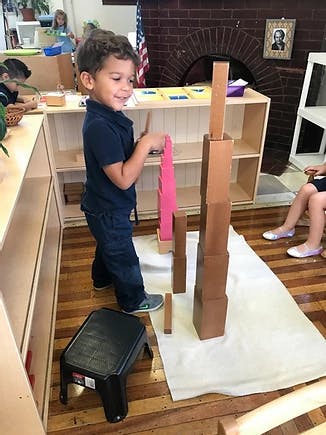 Child building a tower with blocks in a classroom