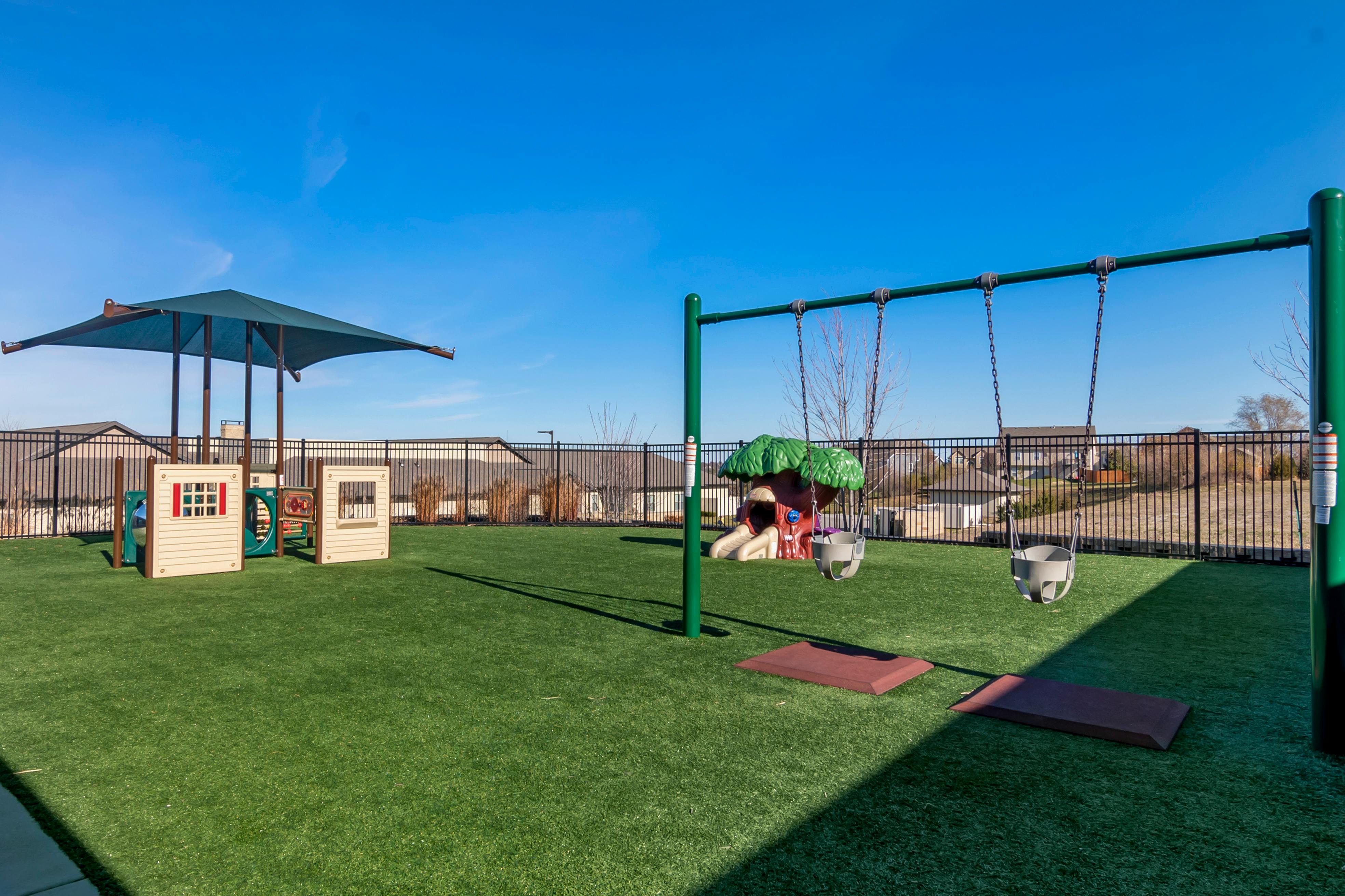 Playground with swings, a playhouse, and a tree-shaped climbing structure