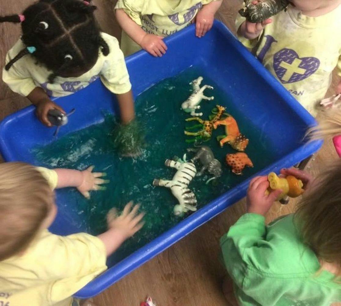 Children playing with animal toys in a blue bin with water