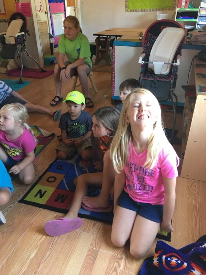Children sitting on the floor and a rug in a classroom